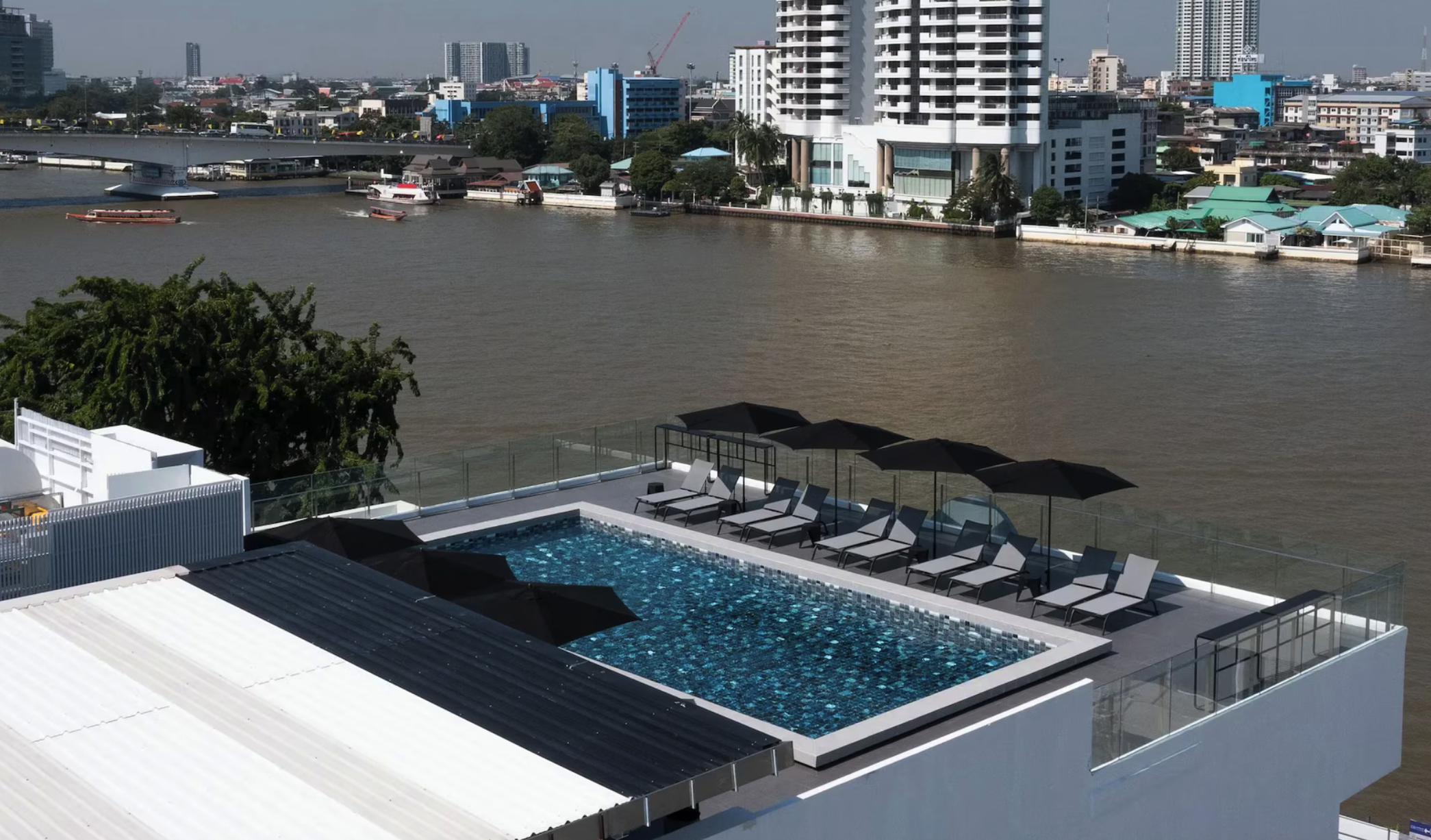Dachpool mit Sonnenliegen und Blick auf den Chao Phraya beim The StandardX Bangkok Phra Arthit