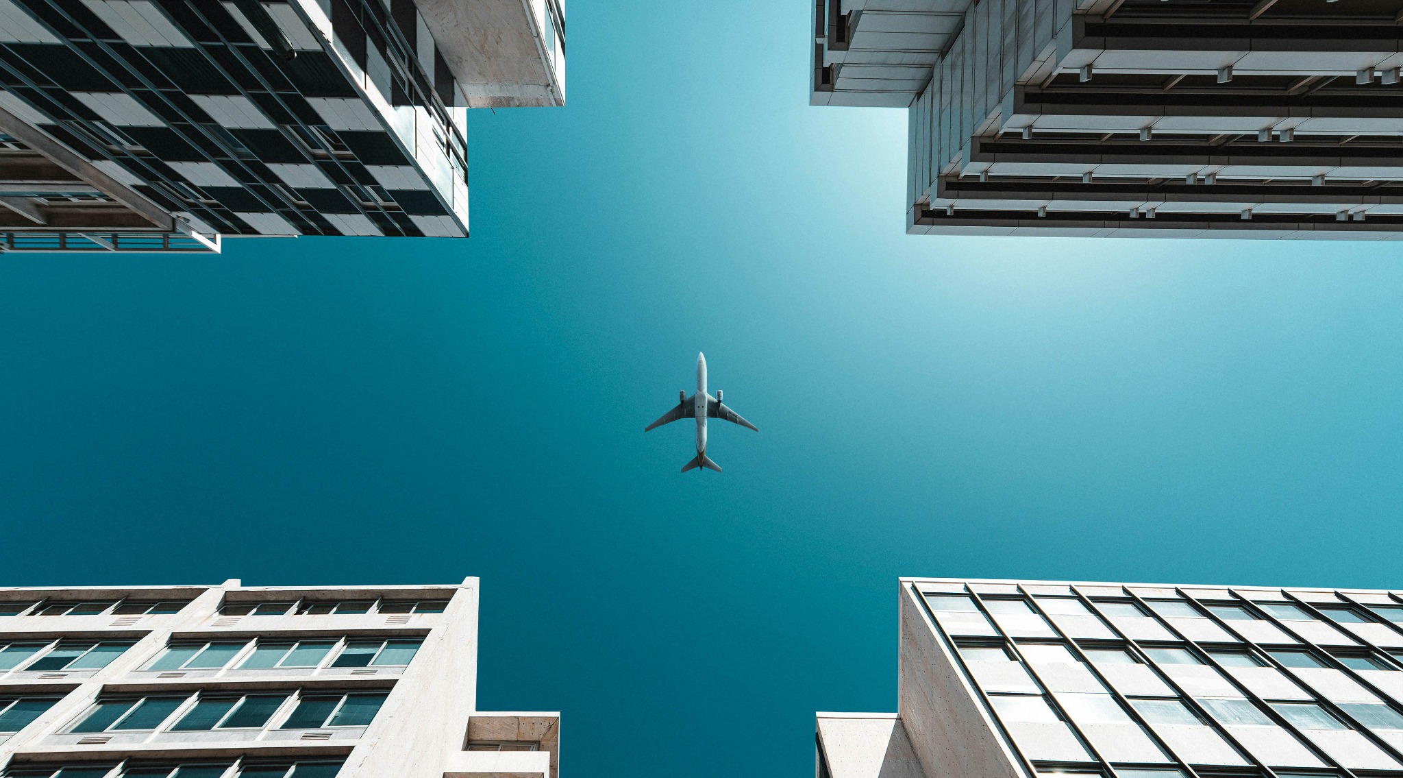 Flugzeug am blauen Himmel zwischen hohen Gebäuden