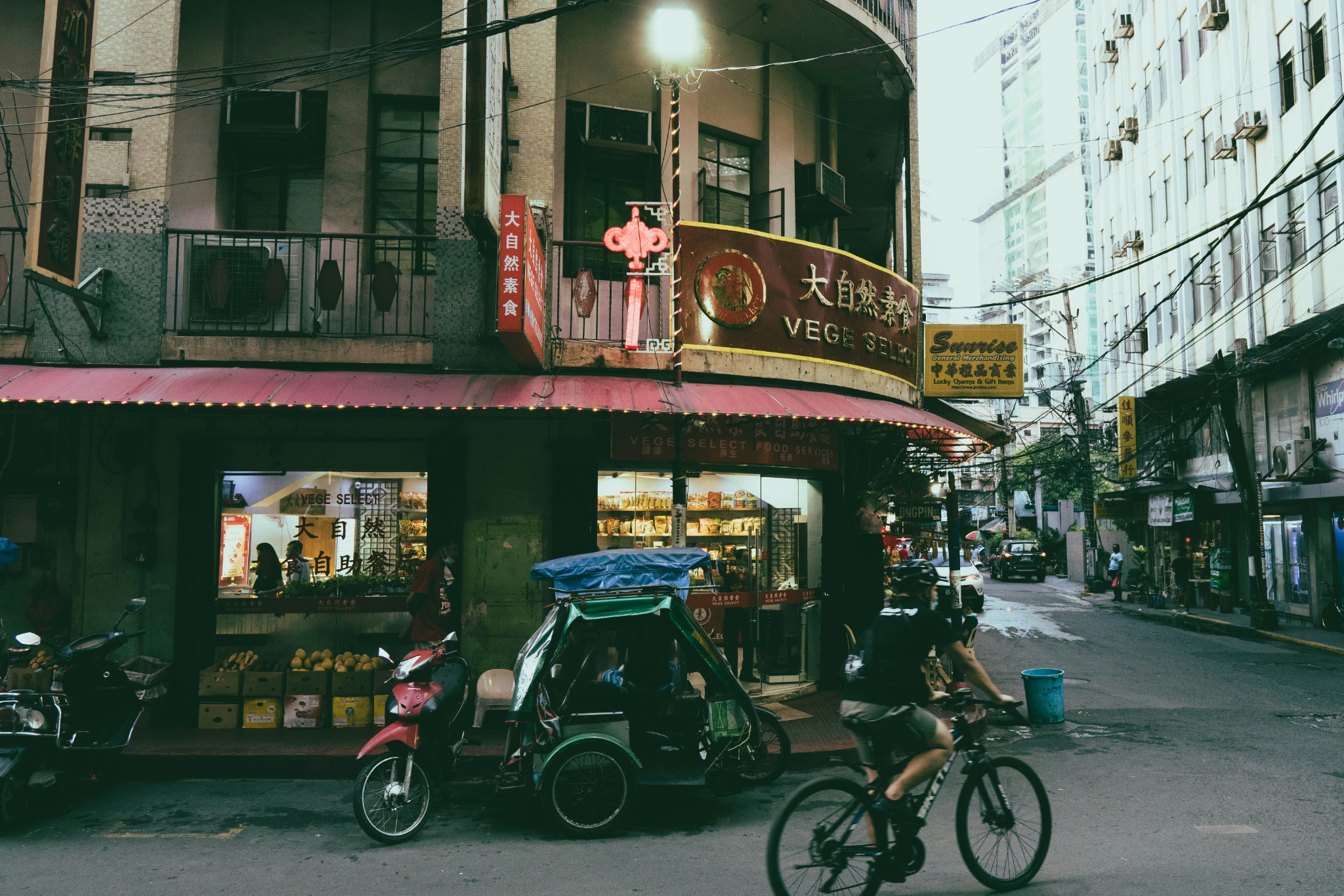 Straßenszene in Manila mit Geschäften und einem Fahrradfahrer