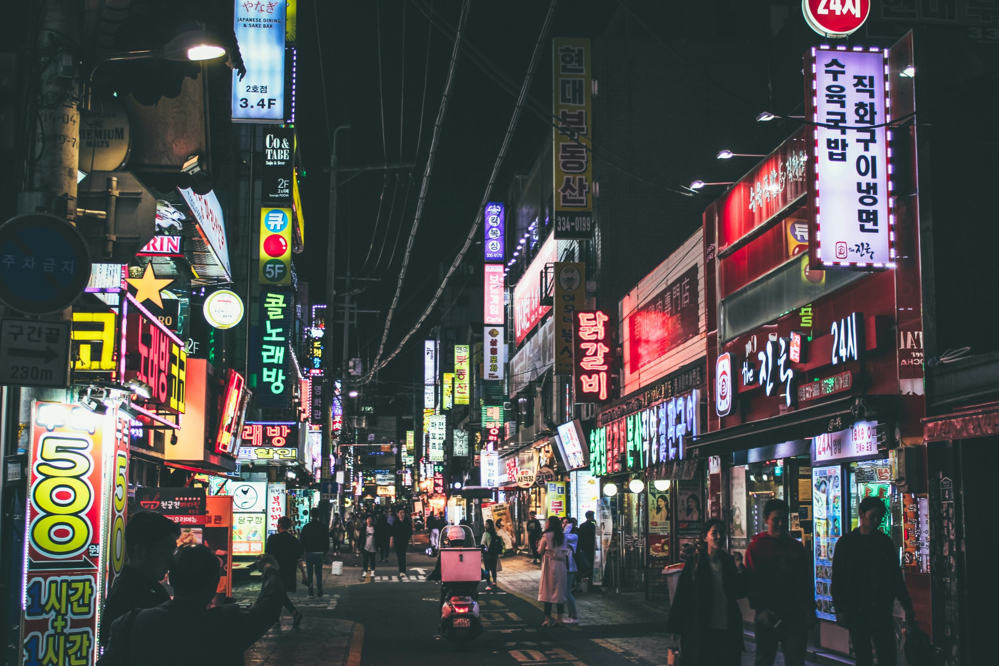 Belebte Straße in Seoul mit leuchtenden Schildern bei Nacht
